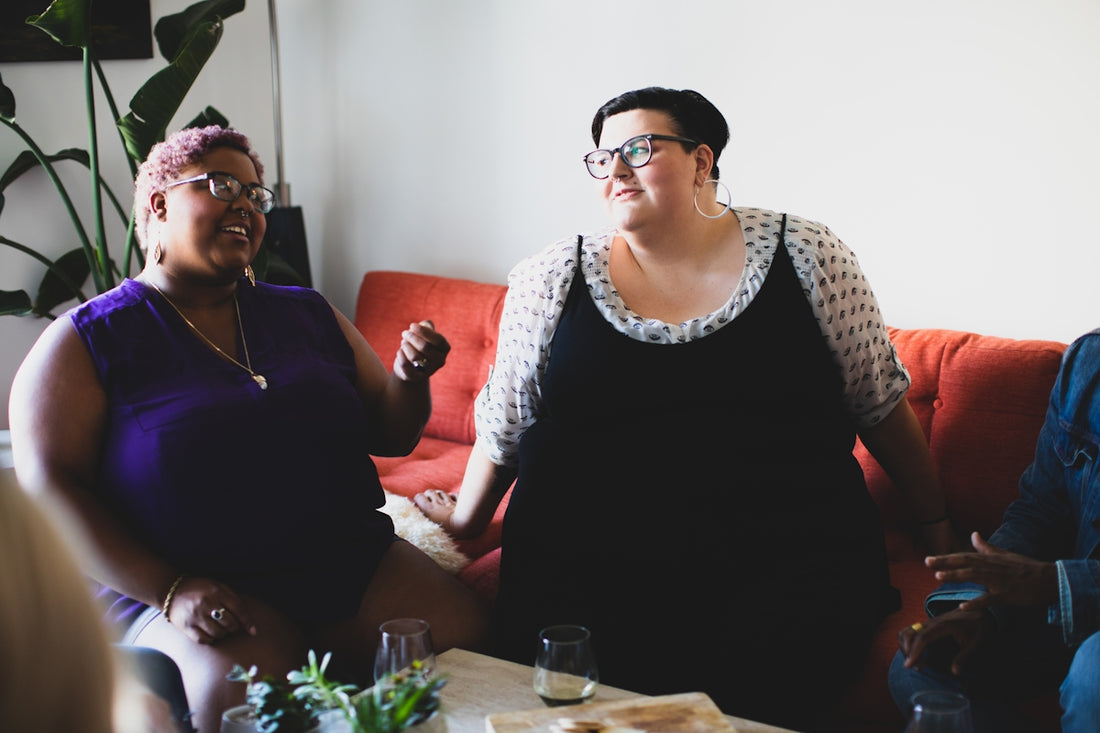 two women sitting on sofa looking at each other