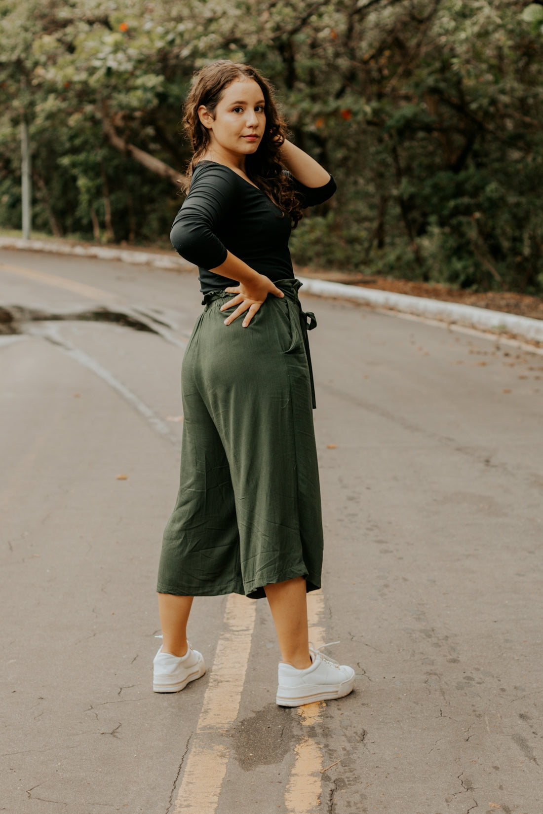 woman in black shirt and gray skirt walking on gray asphalt road during daytime