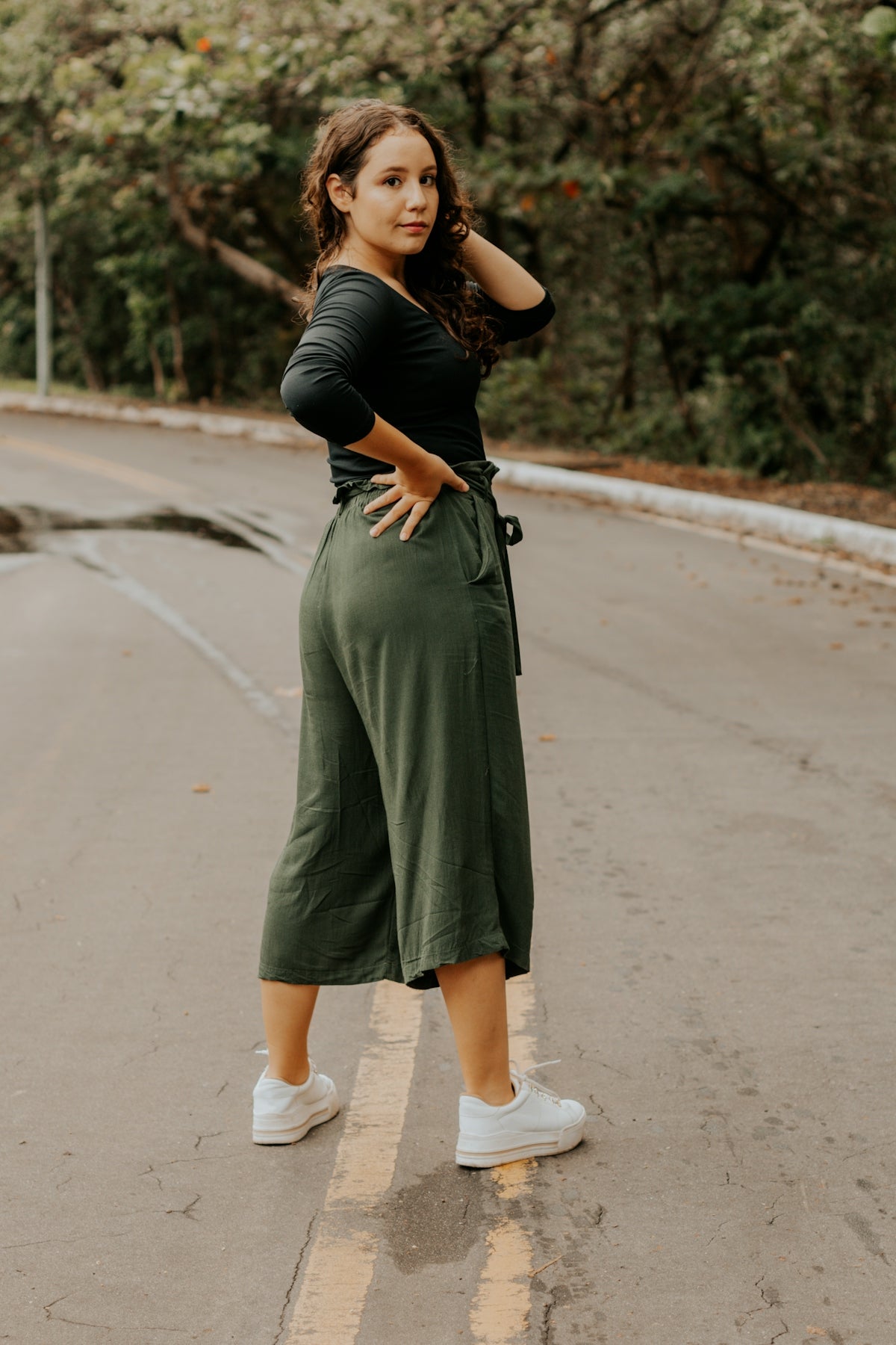 woman in black shirt and gray skirt walking on gray asphalt road during daytime