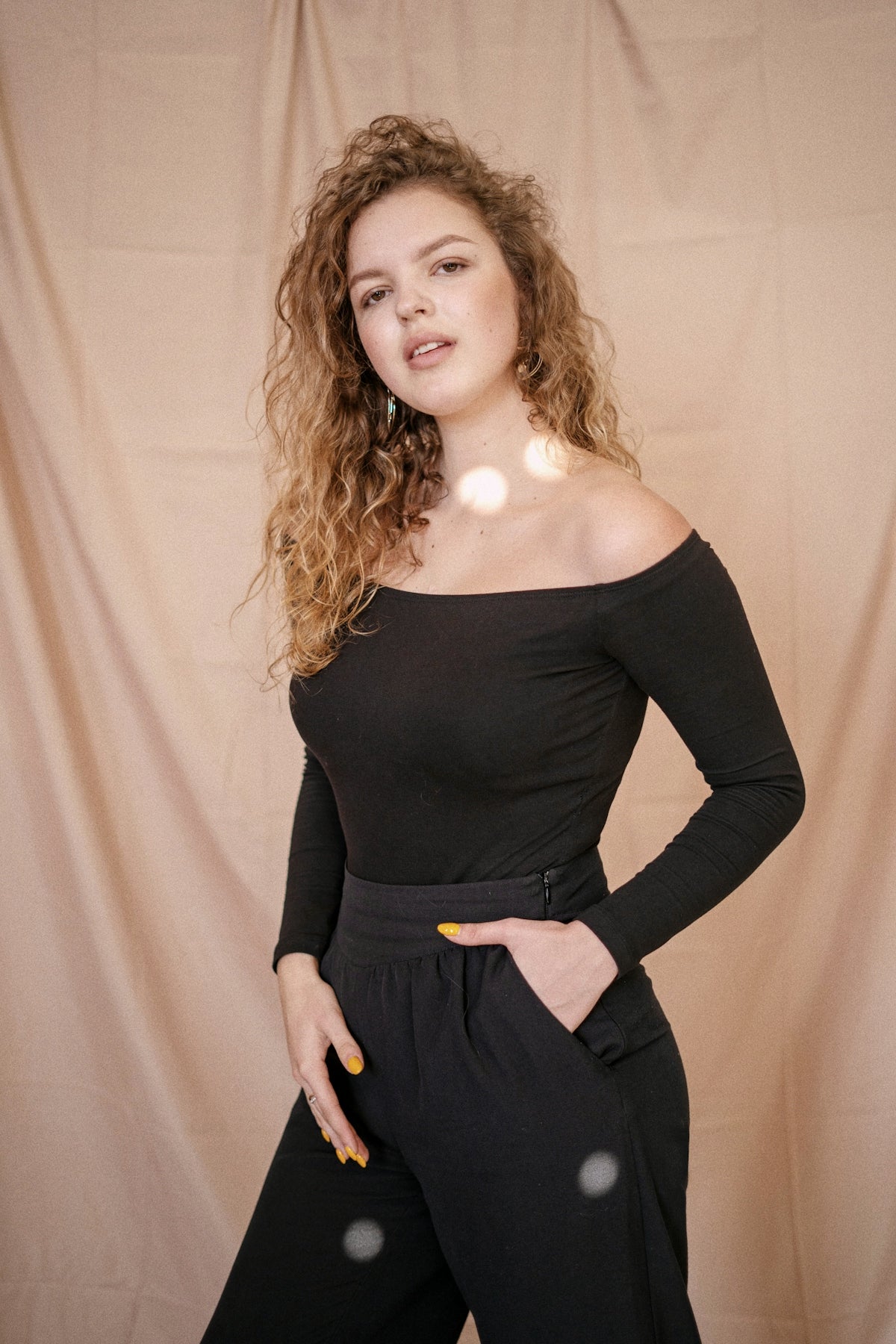 a woman posing for a picture in front of a curtain