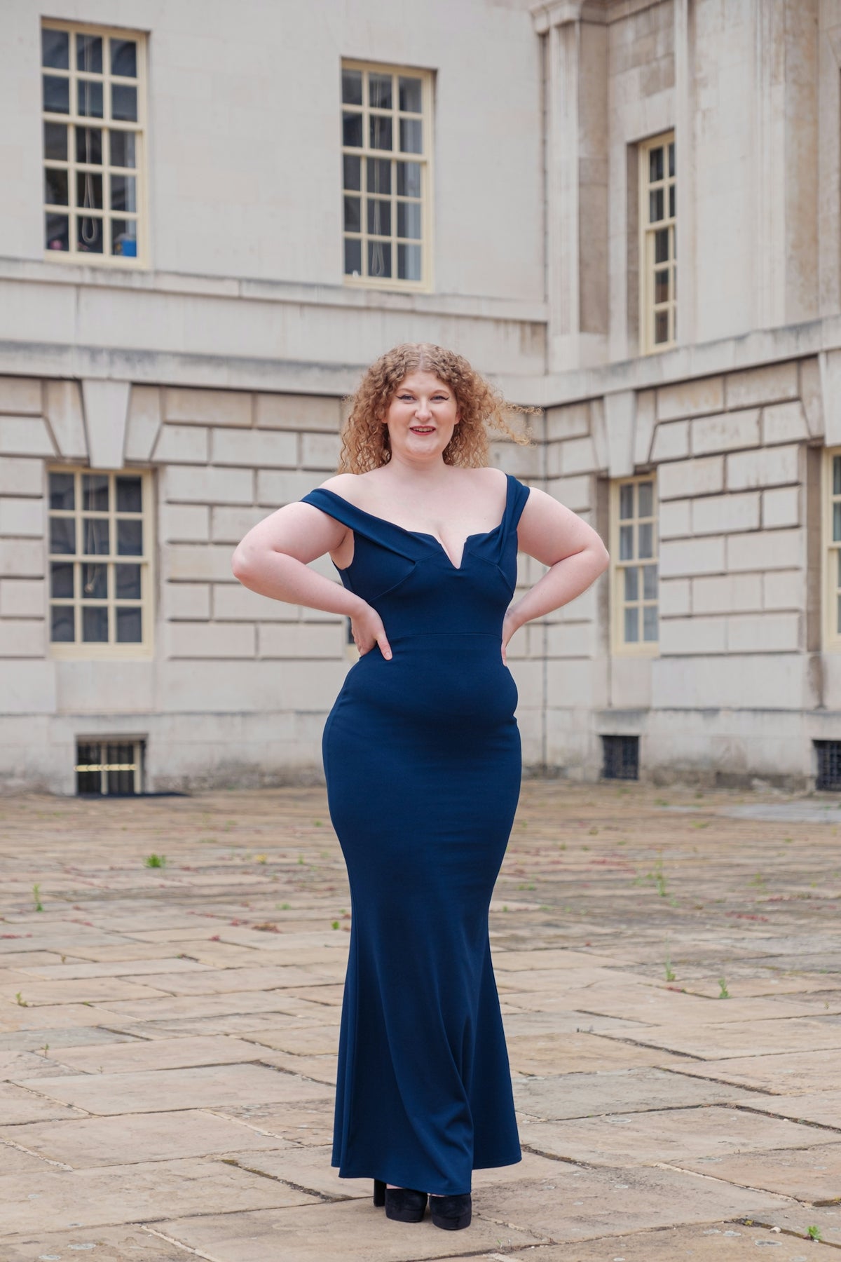 a woman in a blue dress standing in front of a building
