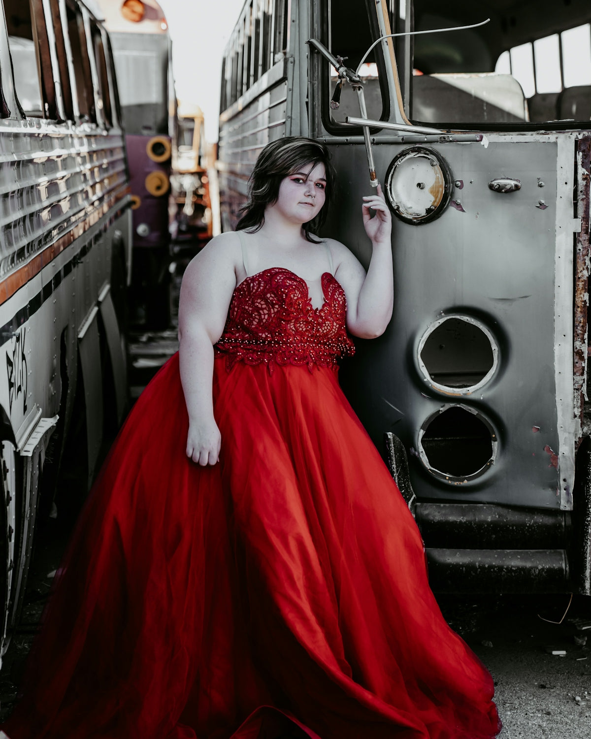 a woman in a red dress leaning against a bus