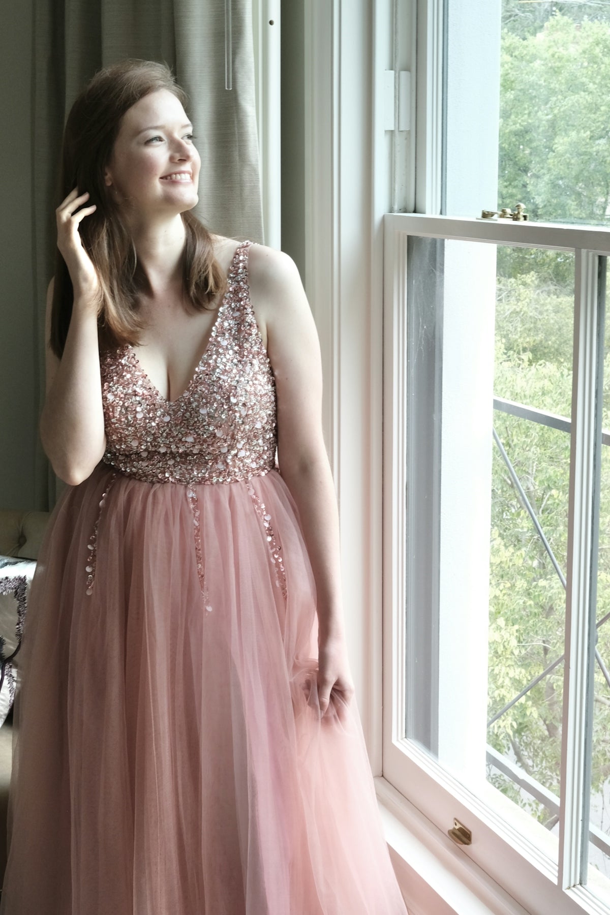 a woman in a pink dress standing next to a window