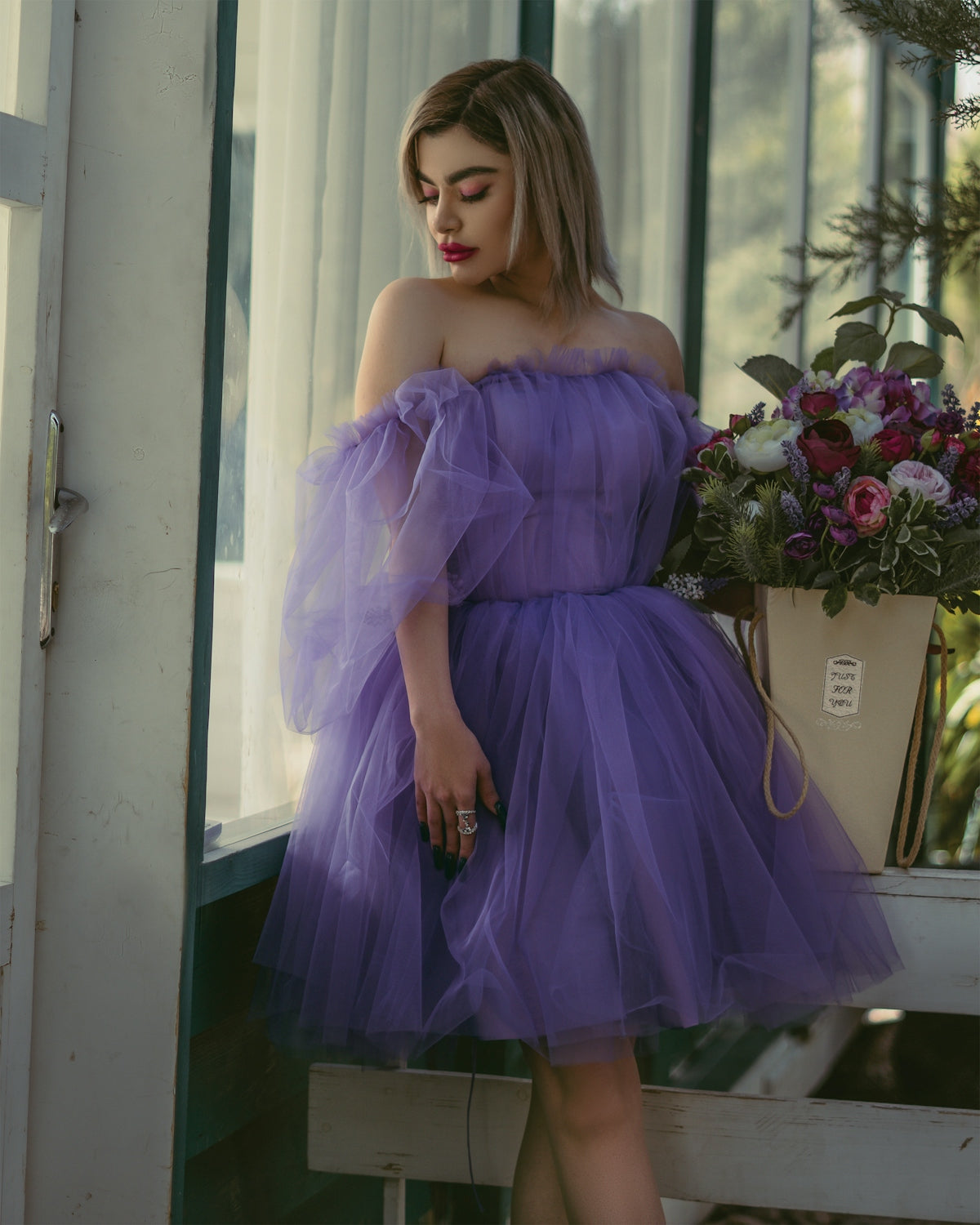 a woman in a purple dress leaning on a window sill