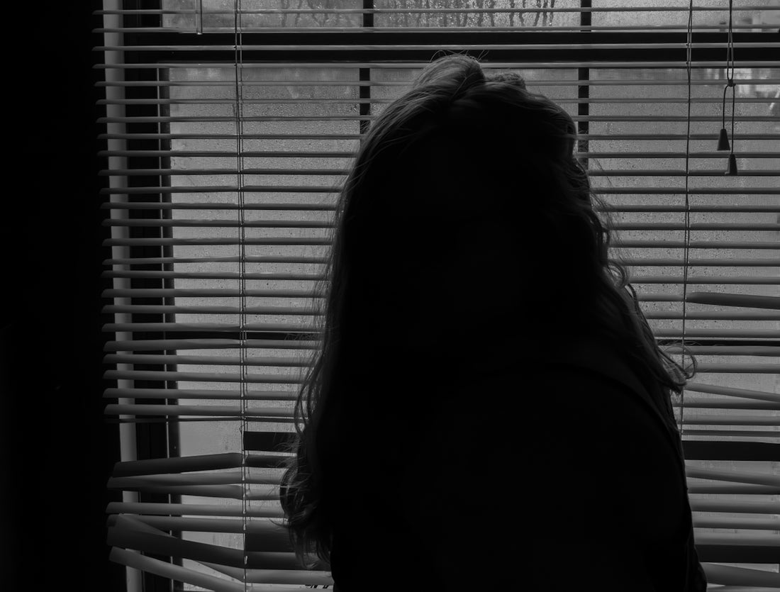 a woman standing in front of a window with blinds