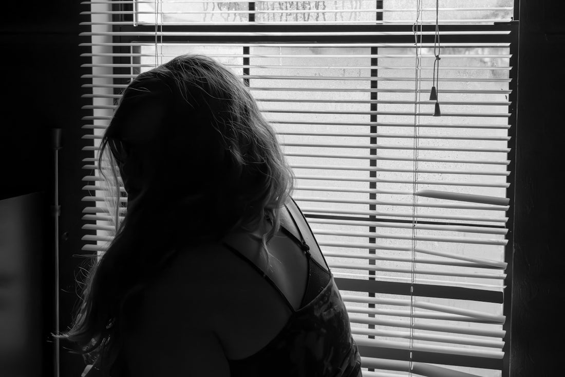 a woman standing in front of a window with blinds
