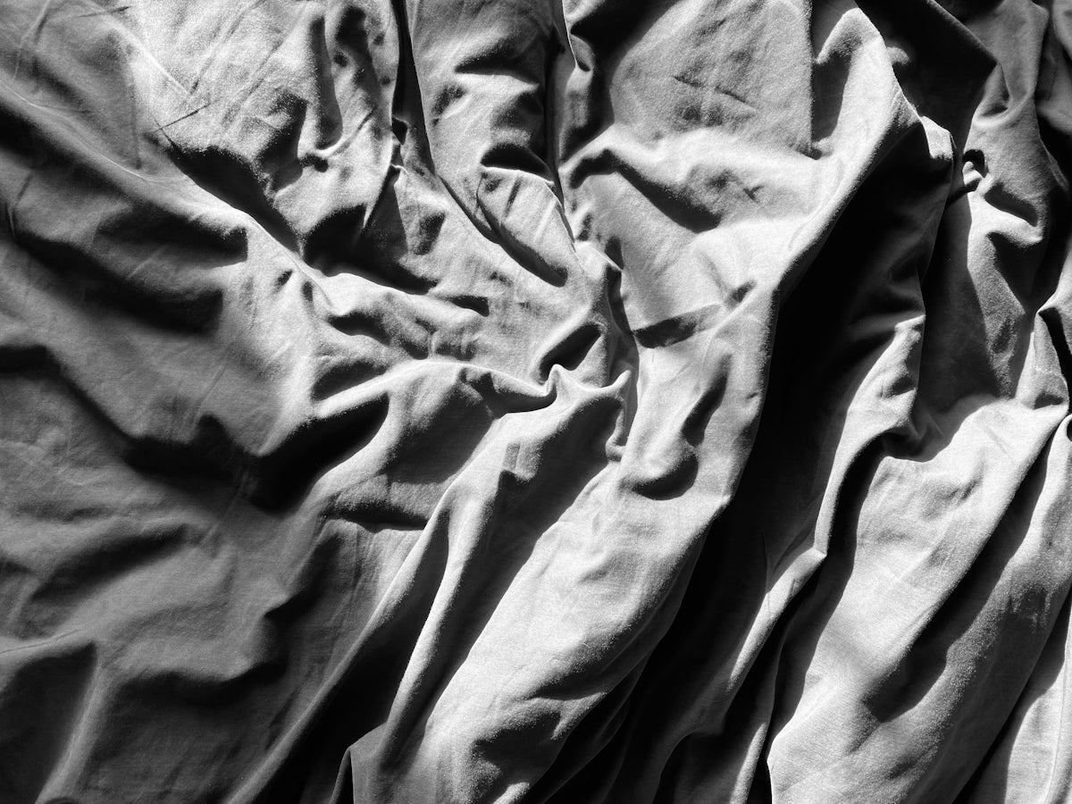 A black and white photo of an unmade bed